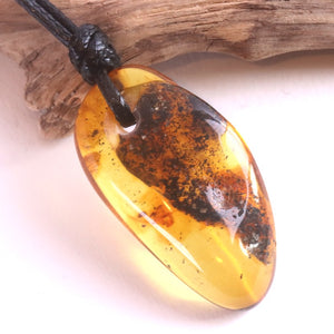 Amber pendant on a black cord with a wooden background