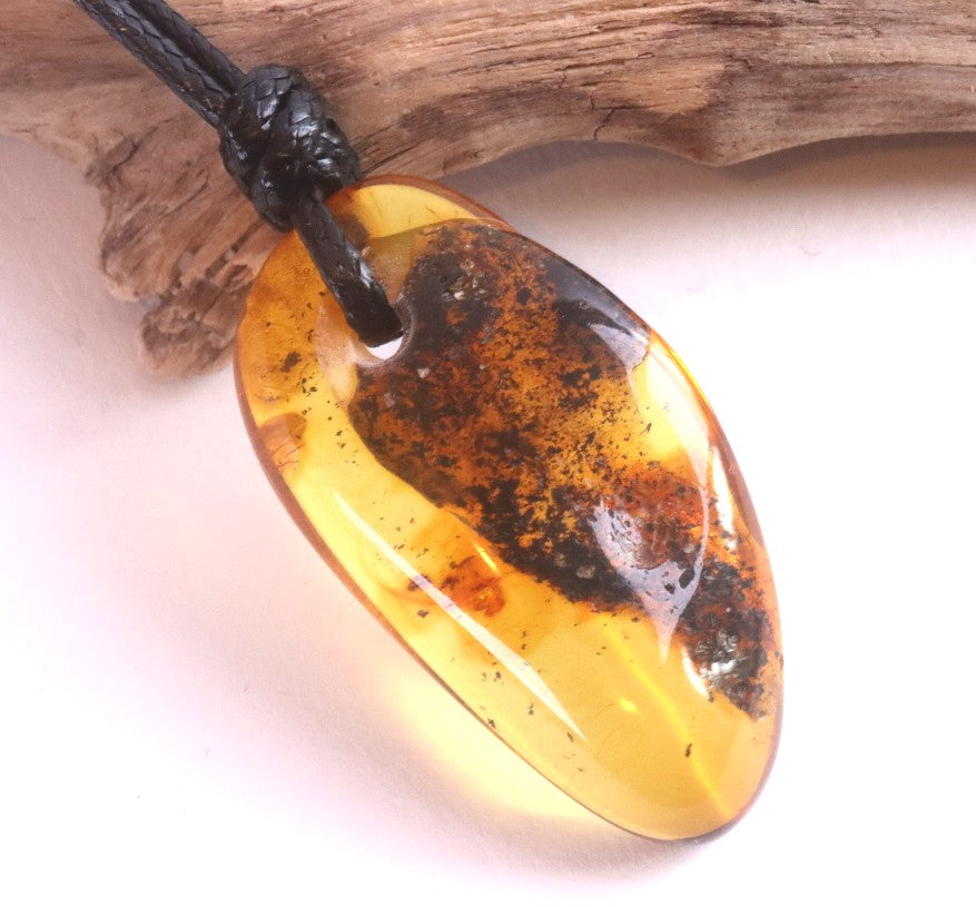 Amber pendant on a black cord with a wooden background