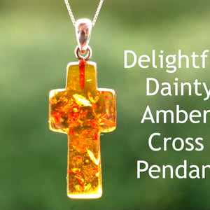 A hand-shaped amber cross pendant on a silver chain, with text describing the amber as 'Delightful Dainty Amber' and the pendant as 'Cross Pendant'.