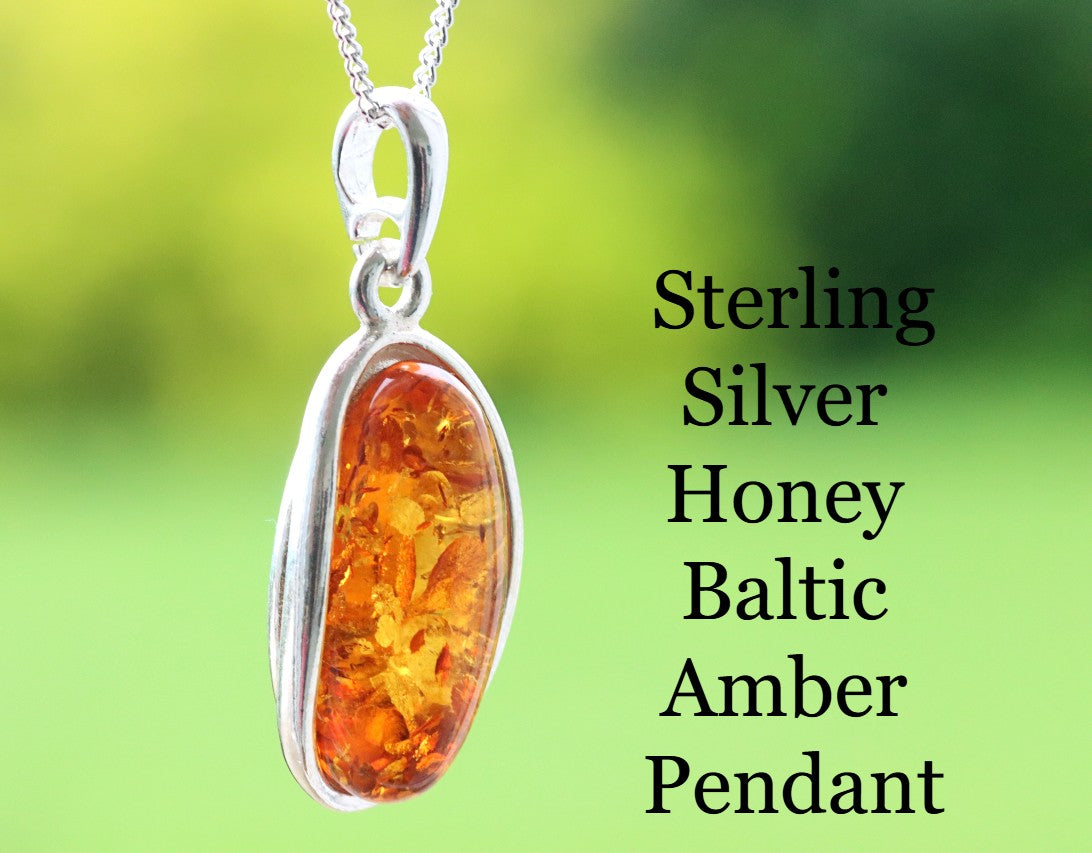 Sterling silver honey Baltic amber pendant on a green background
