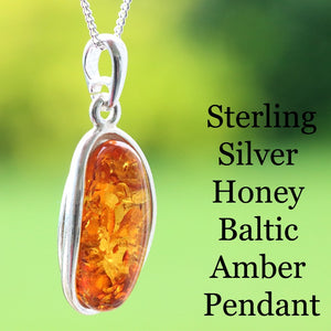 Sterling silver honey Baltic amber pendant on a green background