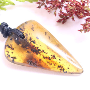 Triangular amber pendant on a white background with green and red leaves.