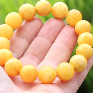 Large opaque Yellow beaded bracelet on a hand with a blurred green background