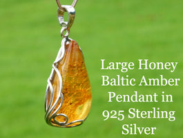 Large honey Baltic Amber pendant in 925 Sterling Silver on a green background