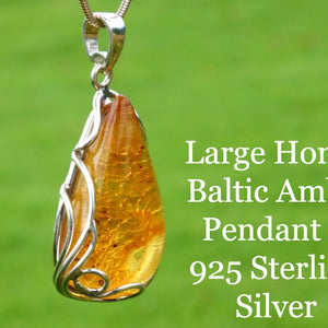 Large honey Baltic Amber pendant in 925 Sterling Silver on a green background