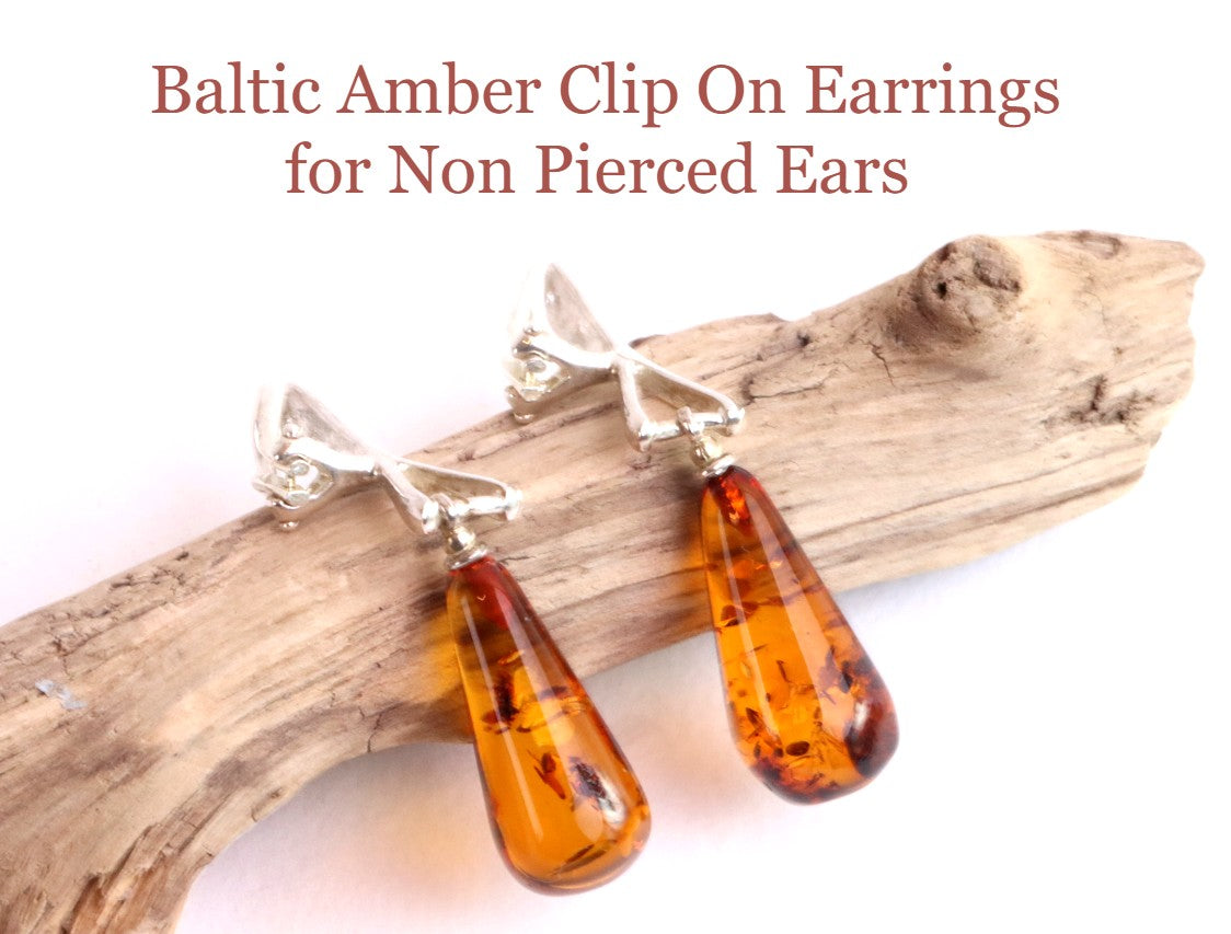 Baltic Amber Clip On Earrings for Non Pierced Ears on a wooden branch with text above.