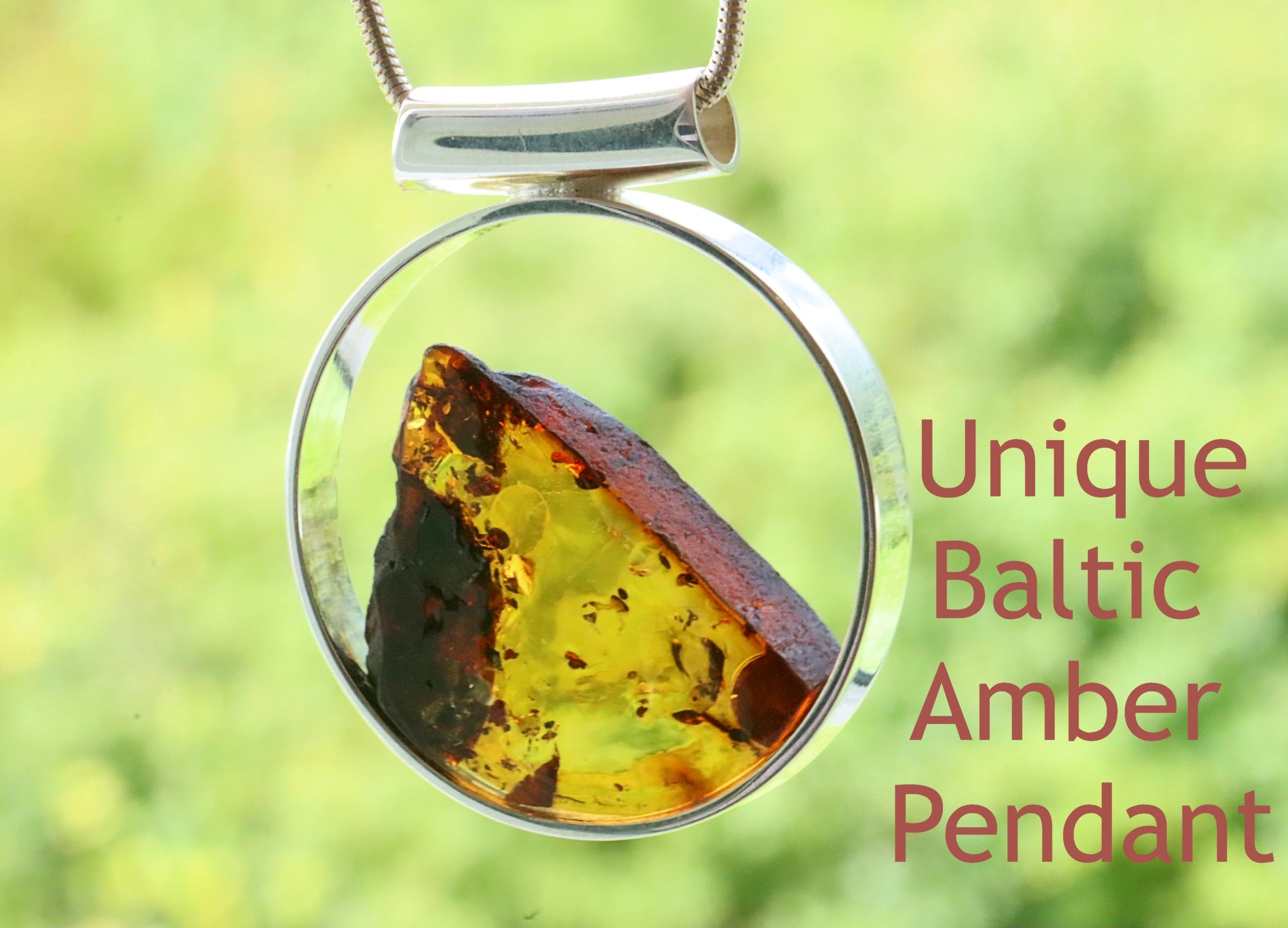 A contemporary silver pendant featuring a slice of amber in the center, with a reflective, glossy finish.