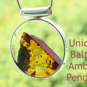 A contemporary silver pendant featuring a slice of amber in the center, with a reflective, glossy finish.