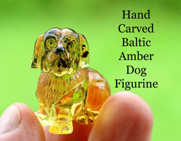 Hand carved Baltic Amber Dog Figurine held between fingers with green background