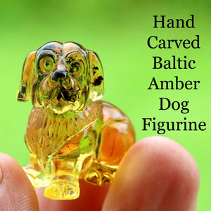 Hand carved Baltic Amber Dog Figurine held between fingers with green background