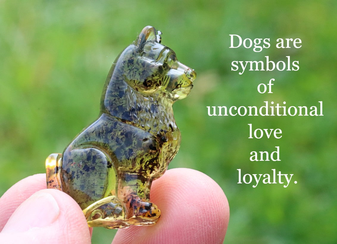 A small, hand-carved amber figurine of a dog, held in someone's hand, with a green and yellow background.