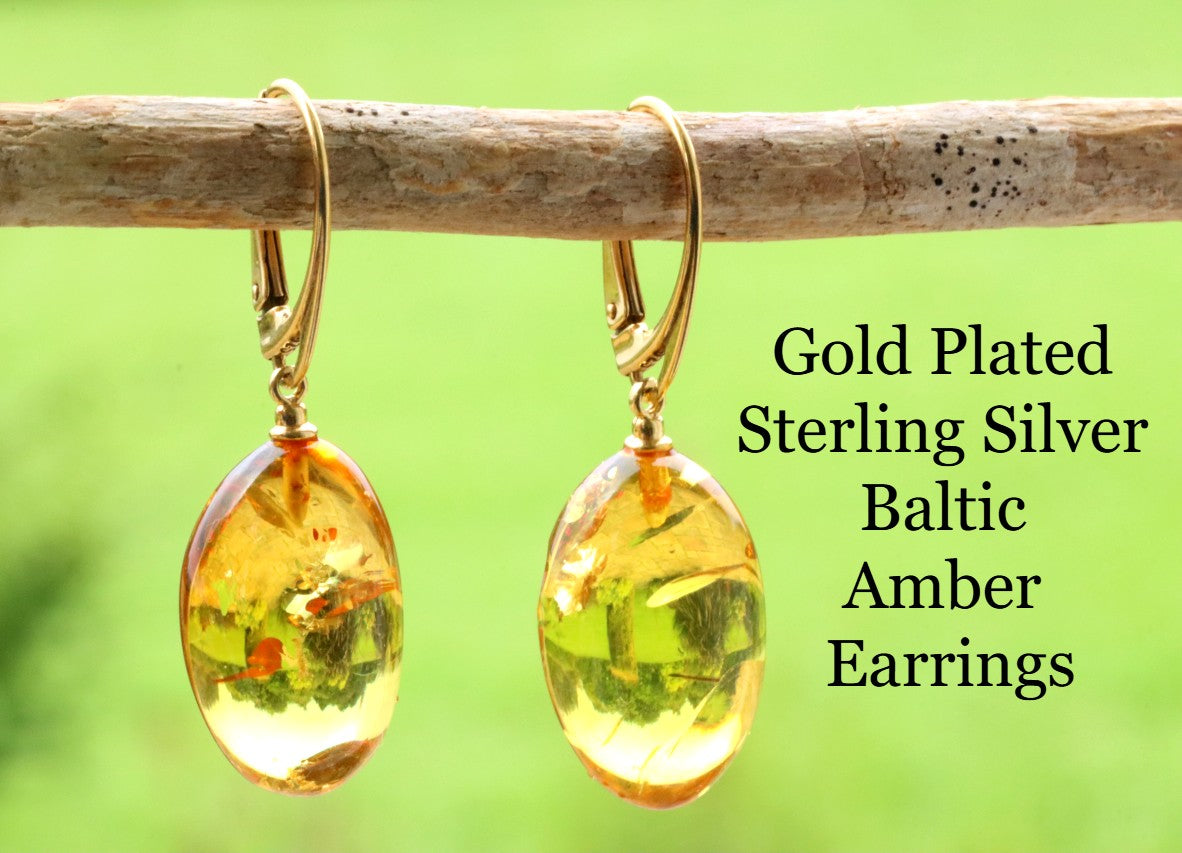 Gold platted sterling silver Baltic amber earrings on a branch with a green background