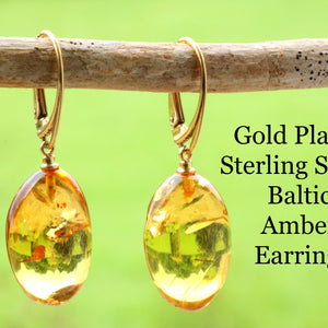 Gold platted sterling silver Baltic amber earrings on a branch with a green background