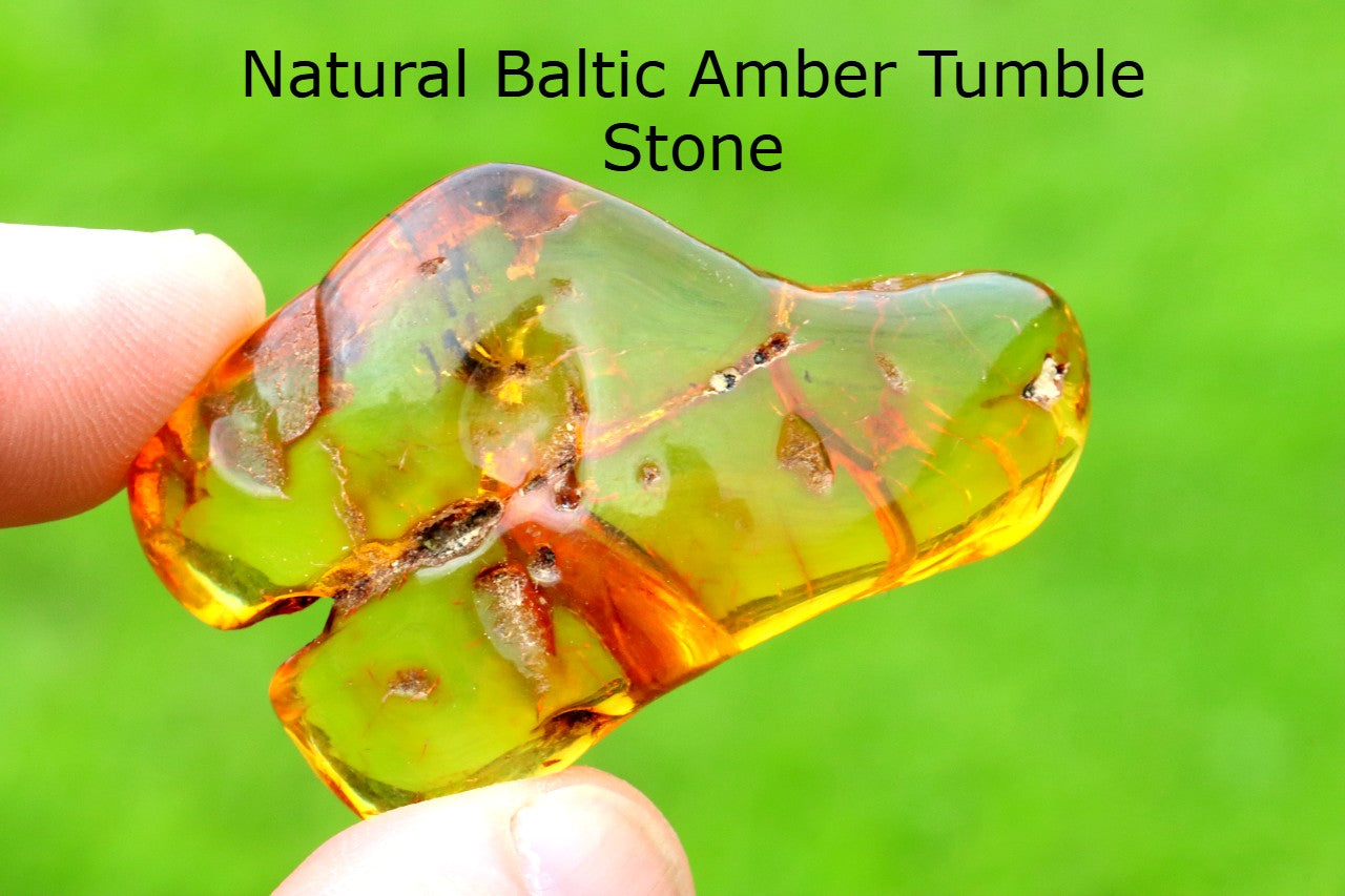 Hand holding a  Healing Energy Amber Stone against a green background