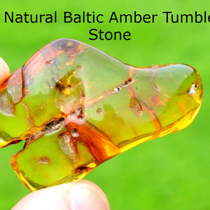 Hand holding a  Healing Energy Amber Stone against a green background