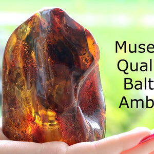 Large Amber Gemstone held in a hand with a blurred green background