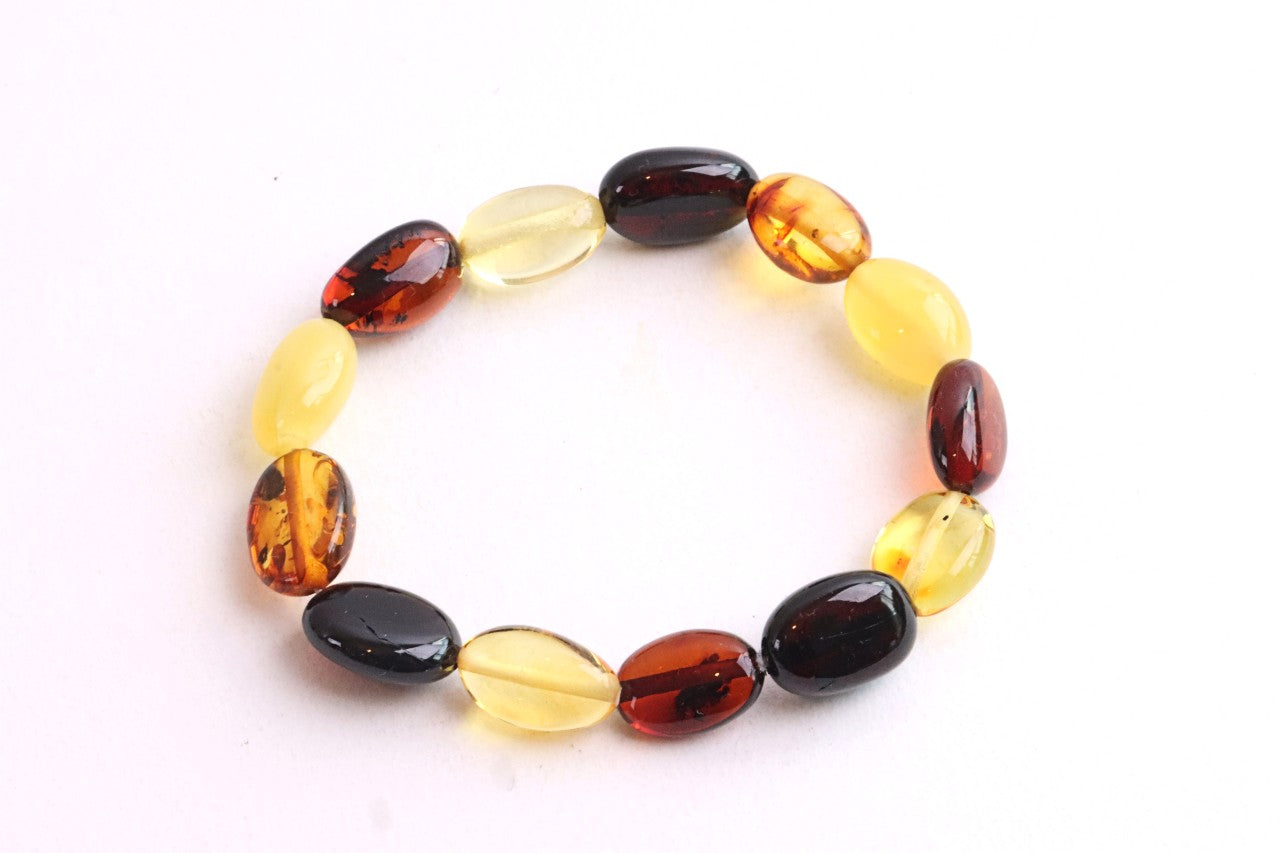 A beaded stretch bracelet made of polished oval beads in amber yellow, translucent light yellow, deep reddish brown, and glossy black, displayed on a clean white background.