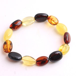 A beaded stretch bracelet made of polished oval beads in amber yellow, translucent light yellow, deep reddish brown, and glossy black, displayed on a clean white background.