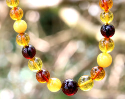 Necklace with multicolored beads against a blurred natural background