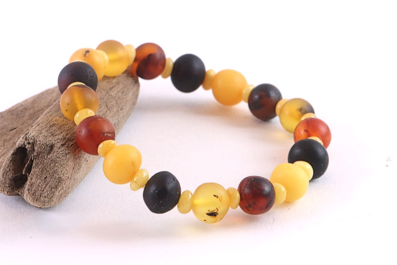 Multicolored beaded bracelet on a white background with a piece of driftwood.
