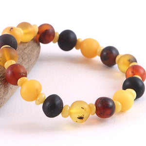 Multicolored beaded bracelet on a white background with a piece of driftwood.