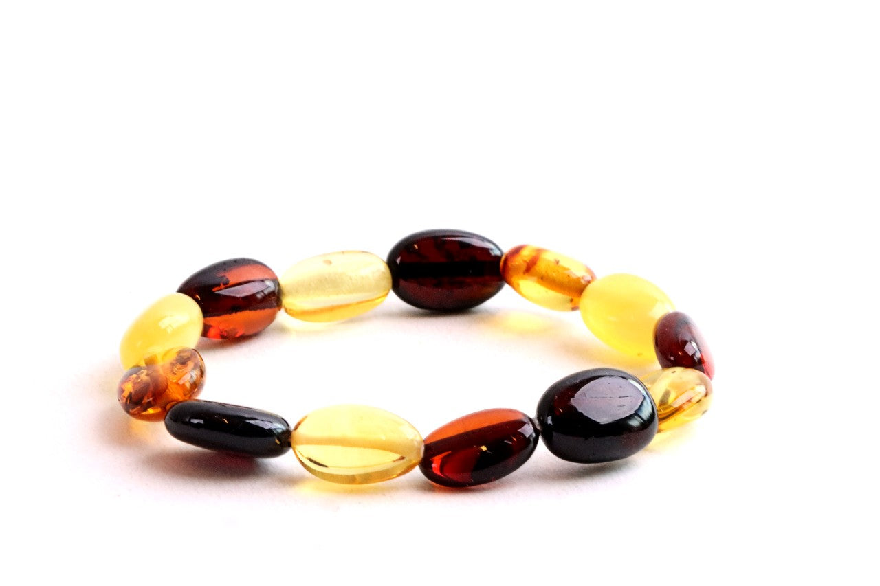 A beaded stretch bracelet made of polished oval amber-like beads in translucent yellow, deep amber-brown, and glossy black, photographed on a clean white background.