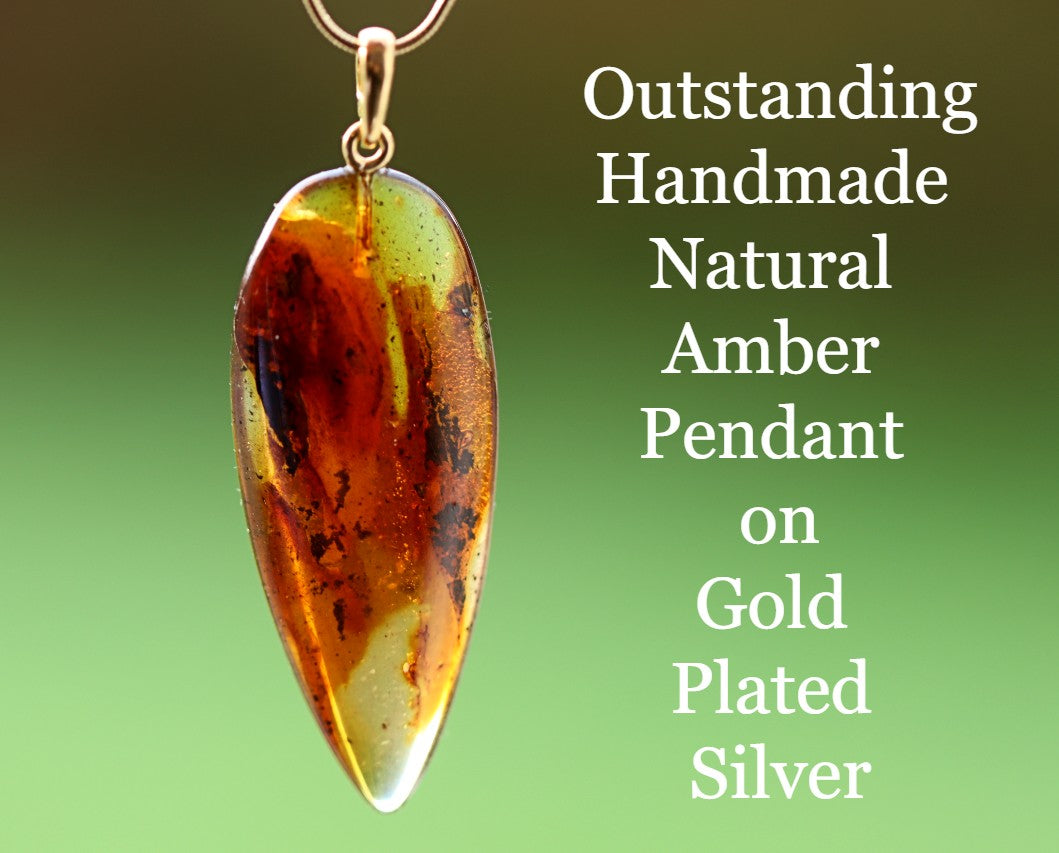 A handmade natural amber gemstone pendant on a gold plated silver chain, advertised with text highlighting the amber's natural color and the type of silver used.