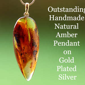 A handmade natural amber gemstone pendant on a gold plated silver chain, advertised with text highlighting the amber's natural color and the type of silver used.