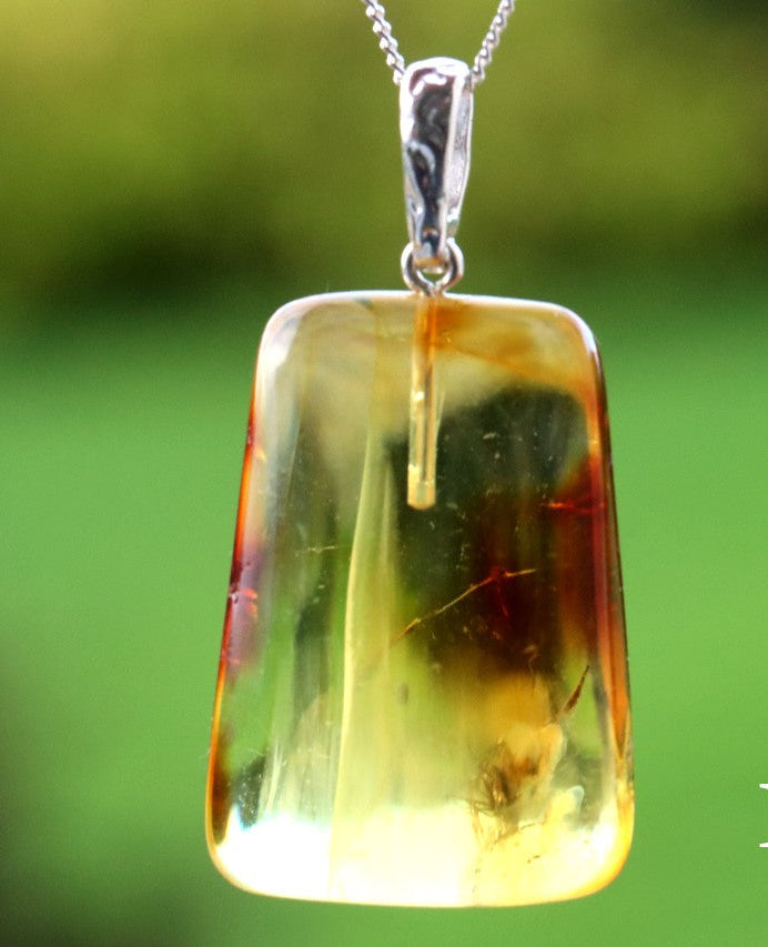Amber pendant with silver chain on a green background