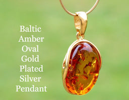 Oval Baltic Amber Gold Plated Silver Pendant on a green background