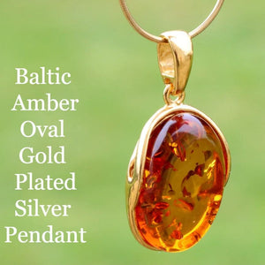 Oval Baltic Amber Gold Plated Silver Pendant on a green background