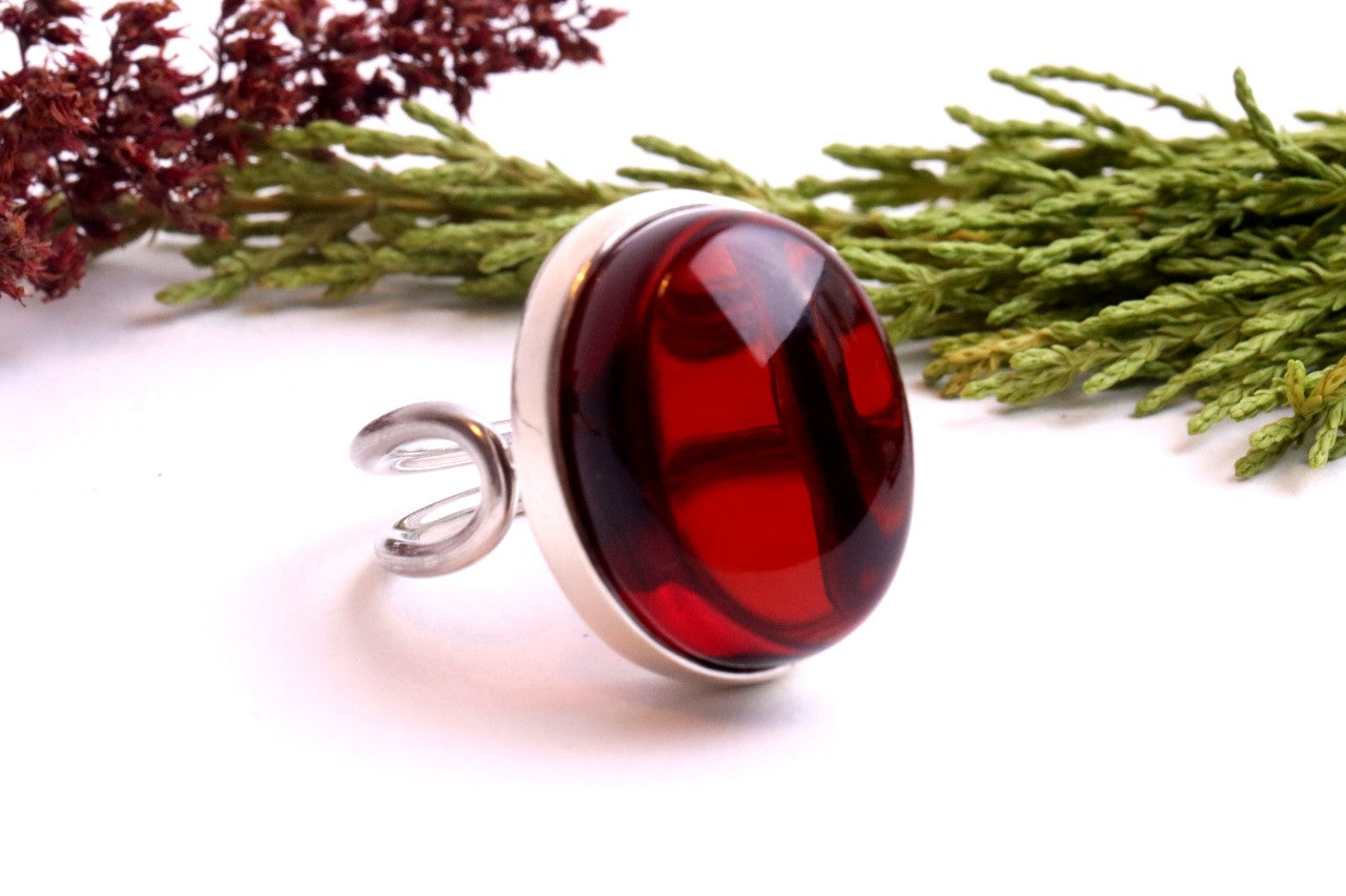 Ring with a red gemstone on a white background with greenery