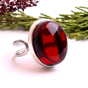 Ring with a red gemstone on a white background with greenery