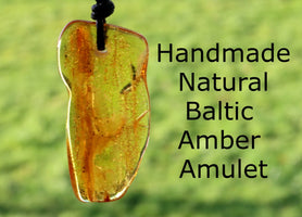A hand-shaped amber amulet pendant with 'Handmade Natural Baltic Amber Amulet' text overlayed on a background of greenery.