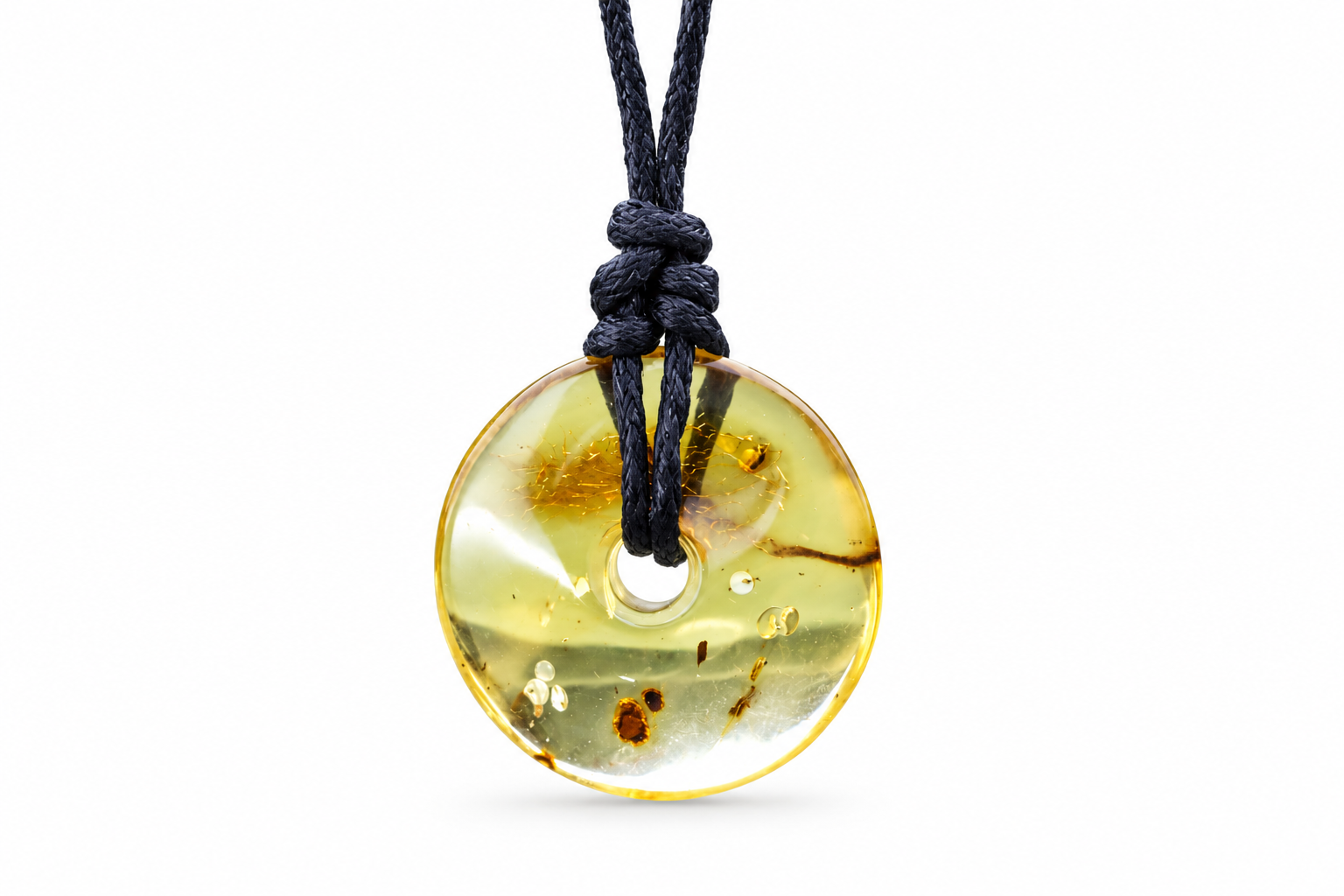 A round translucent amber pendant necklace with a black cord, featuring natural inclusions and a polished finish, shown against a plain white background.