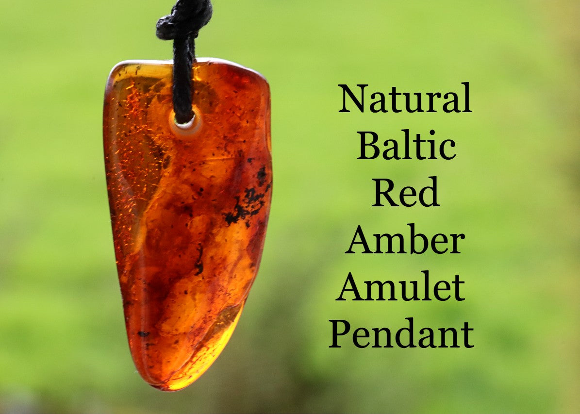 Natural Baltic Red Amber Amulet Pendant on a blurred green background