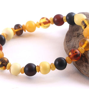 Multicolored beaded bracelet on a white background with a piece of driftwood.