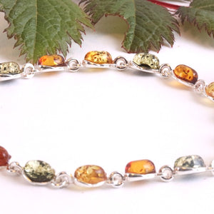 Multicolored beaded bracelet on a white background with green leaves and a purple flower.