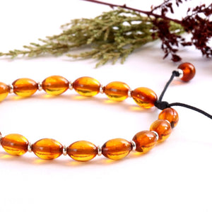 Sparkly amber bracelet on a white background with dried plants.