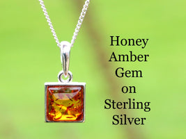 Honey amber gemstone pendant on a silver chain against a green background with text.