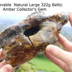 A very large, polished stone of Baltic amber displayed in a person's hand, with a certificate of authenticity mentioned.