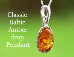 Silver pendant with Baltic Amber drop on a green background