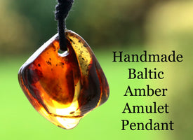 Handmade Baltic Amber Amulet Pendant on a blurred green background