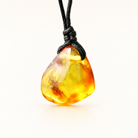 A polished amber stone pendant with natural inclusions, suspended from a black cord, shown against a clean white background.