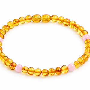 A beaded bracelet made of translucent amber-yellow round beads with a few light pink accent beads, photographed on a clean white background.