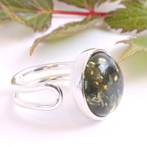 Silver ring with a green gemstone on a white background with leaves.