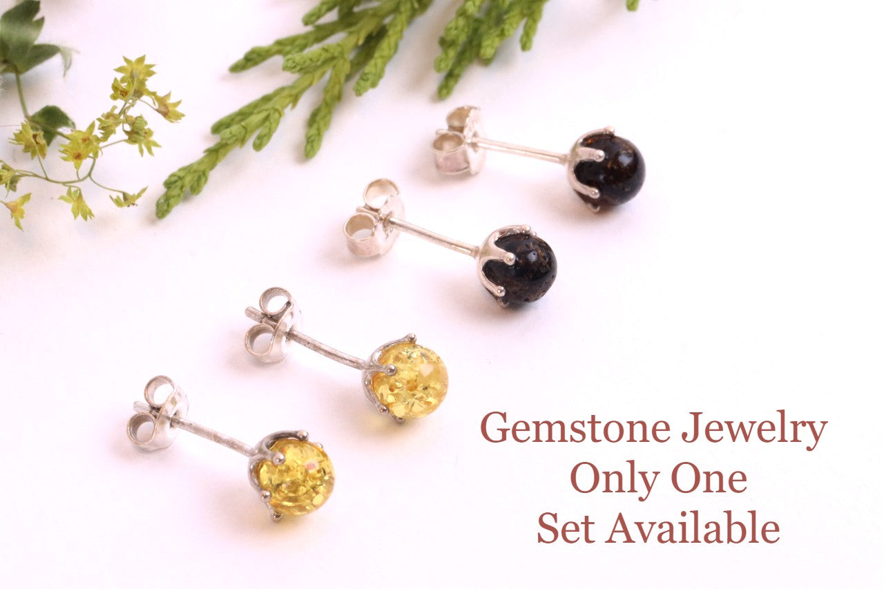 Pair of gemstone earrings on a white background with greenery