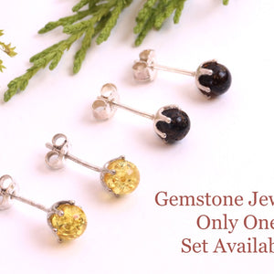 Pair of gemstone earrings on a white background with greenery