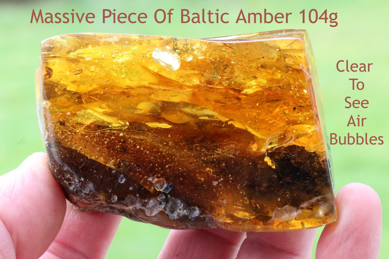 A hand holding a polished piece of Baltic amber with natural color variations and inclusions.