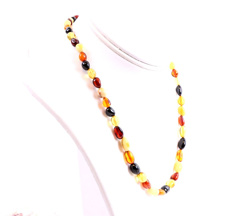 A necklace with flat, round amber beads in various shades of yellow, honey, cognac, and white strung together, displayed on a mannequin.
